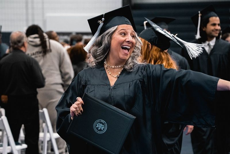 Graduate points and smiles holding diploma